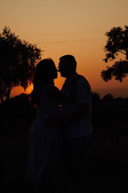 Günbatımı siluetinde aşık çift