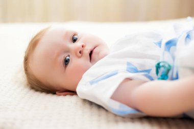 Küçük kız 6 aylık, büyük mavi gözlü, mutlu.