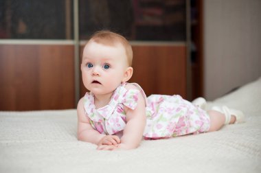 Küçük kız 6 aylık, büyük mavi gözlü, mutlu.