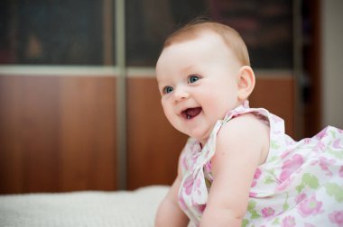 Küçük kız 6 aylık, büyük mavi gözlü, mutlu.