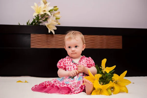 9个月大的小女孩躺在床上 床上开着黄色的花 — 图库照片