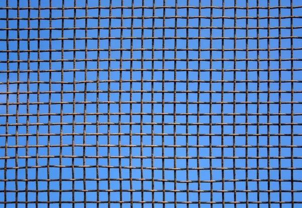 Photo of steel mesh wall on sky background — Stock Photo, Image