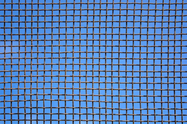 Photo of steel mesh wall on sky background — Stock Photo, Image