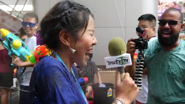 A lady tried to keep reporting at Silom road, Bangkok, despite water gun shots from every direction during Songkran festival. — Stock Video