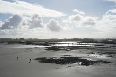 Normandie, Fransa-Ocak 26, 2018: İnsanlar yürüyüş köprü ve düşük gelgit Mont-Saint-Michel yakınındaki kum plaj.