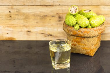 Noni meyve sepeti ve noni suyu siyah masada. Meyve sağlık ve bitki sağlığı için