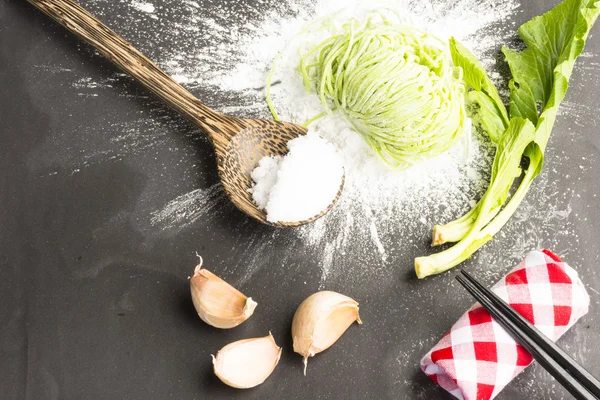 Green dried noodles same egg noodles and on flour powder and ingredient on black background.Close up and top view. — Stock Photo, Image