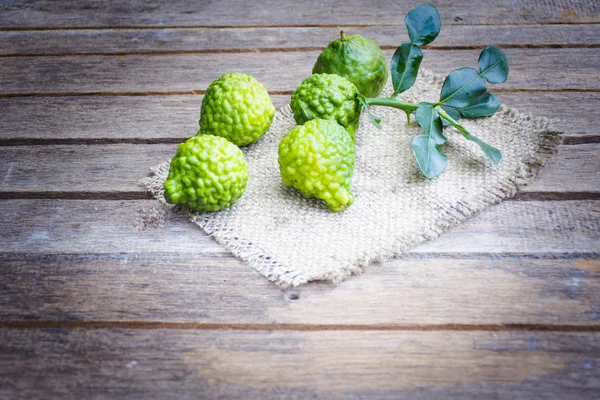 Kapur Kaffir pada meja kayu adalah buah-buahan dan daun digunakan sebagai rempah-rempah untuk makanan thai dan lain-lain — Stok Foto