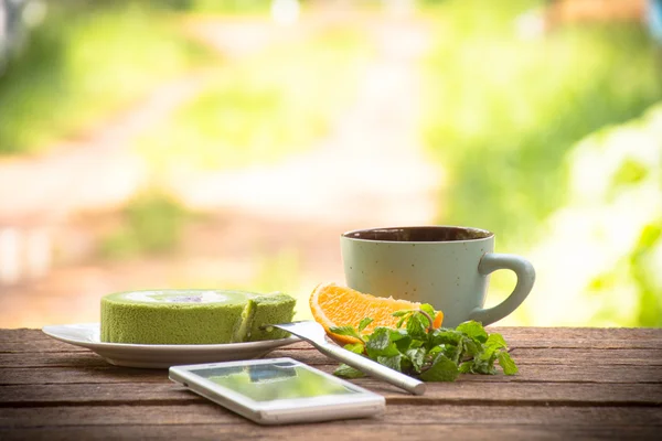 Arka plan fincan yeşil çay pasta ve nane ile smartphone ile meyve ve kahve. Ahşap arka plan açık görünümü ve relax ile tatil 