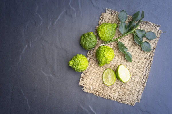 Kaffir limão no fundo preto é frutas e folhas são usadas como um tempero para comida tailandesa e etc — Fotografia de Stock