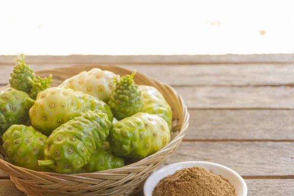 Ahşap masa üzerinde Noni meyve ve noni tozu. Meyve sağlık ve bitki sağlığı için
