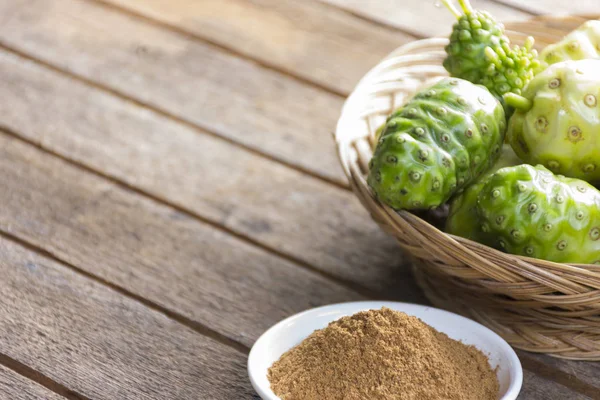 Ahşap masa üzerinde Noni meyve ve noni tozu. Meyve sağlık ve bitki sağlığı için
