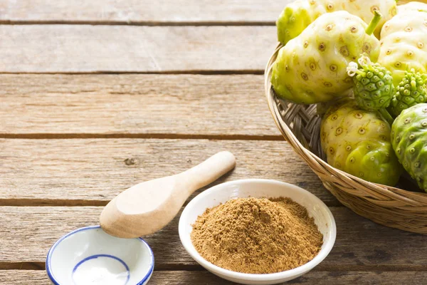 Noni fruit en noni poeder op houten tafel. Fruit voor de gezondheid en kruid voor gezondheid. — Stockfoto