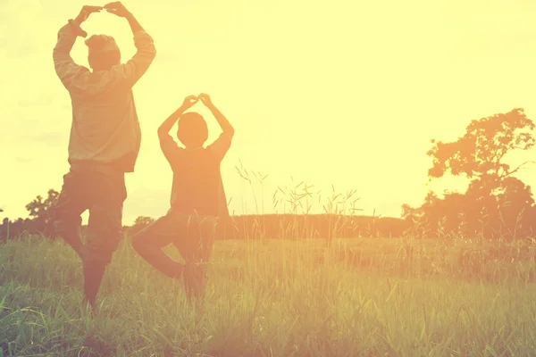 Aile egzersiz ya da dağ manzaralı, ya da baba ve oğul ile yoga faaliyetleri çayır ve güneş görünümü vardır