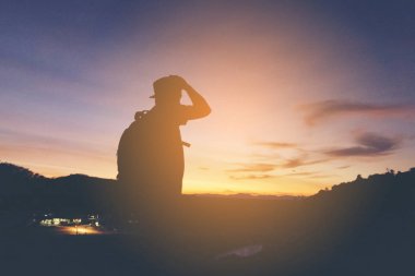 Adam hipster sırt çantası güneş ve dağ manzaralı seyir silüeti... 1