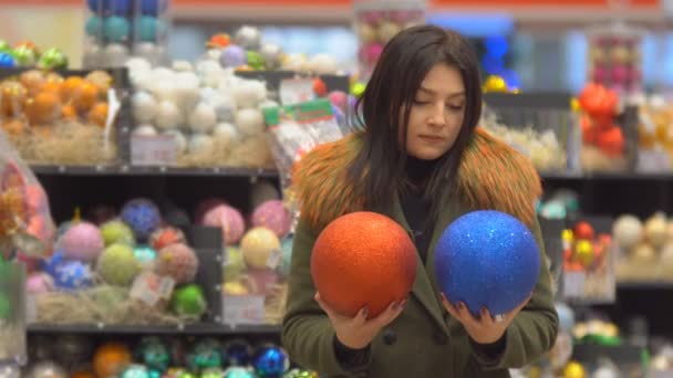 超市里的圣诞装饰品一个女孩选择在超市里买玩具和圣诞彩球装饰圣诞树 — 图库视频影像