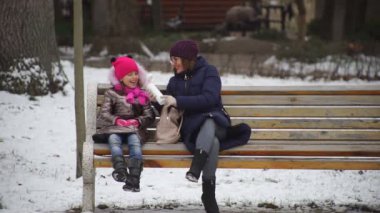 Anne ve kızı açık hava kafede bir bankta otururken eğleniyorlar. Eğlenceli bir tatilden gülümsemeler ve duygular.