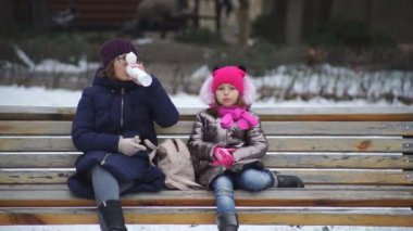 Anne ve kızı açık hava kafede bir bankta otururken eğleniyorlar. Eğlenceli bir tatilden gülümsemeler ve duygular.