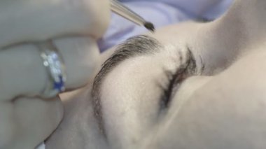 Kaş güzellik salonunda, üstat kaşlarla ilgilenir. Kadın kaşlarının tasarımı ve boyaması ve kaplaması. Renk eşleşmesi. Kozmetik bir araçla düzeltme.
