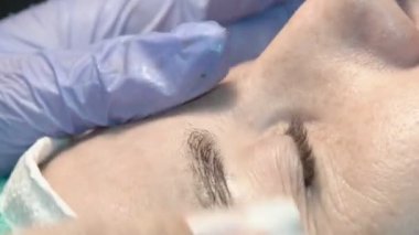 Kaş güzellik salonunda, üstat kaşlarla ilgilenir. Kadın kaşlarının tasarımı ve boyaması ve kaplaması. Renk eşleşmesi. Kozmetik bir araçla düzeltme.