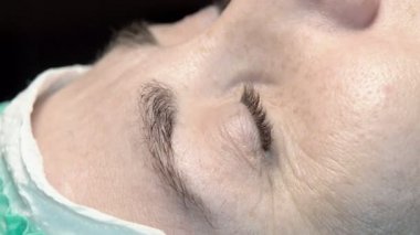 Kaş güzellik salonunda, üstat kaşlarla ilgilenir. Kadın kaşlarının tasarımı ve boyaması ve kaplaması. Renk eşleşmesi. Kozmetik bir araçla düzeltme.