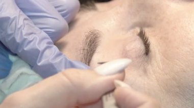 Kaş güzellik salonunda, üstat kaşlarla ilgilenir. Kadın kaşlarının tasarımı ve boyaması ve kaplaması. Renk eşleşmesi. Kozmetik bir araçla düzeltme.