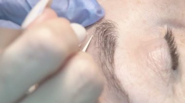 Kaş güzellik salonunda, üstat kaşlarla ilgilenir. Kadın kaşlarının tasarımı ve boyaması ve kaplaması. Renk eşleşmesi. Kozmetik bir araçla düzeltme.