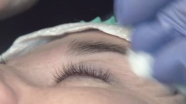 Kaş güzellik salonunda, üstat kaşlarla ilgilenir. Kadın kaşlarının tasarımı ve boyaması ve kaplaması. Renk eşleşmesi. Kozmetik bir araçla düzeltme.