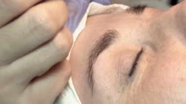 Kaş güzellik salonunda, üstat kaşlarla ilgilenir. Kadın kaşlarının tasarımı ve boyaması ve kaplaması. Renk eşleşmesi. Kozmetik bir araçla düzeltme.