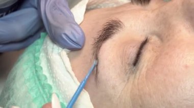 Kaş güzellik salonunda, üstat kaşlarla ilgilenir. Kadın kaşlarının tasarımı ve boyaması ve kaplaması. Renk eşleşmesi. Kozmetik bir araçla düzeltme.