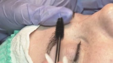 Kaş güzellik salonunda, üstat kaşlarla ilgilenir. Kadın kaşlarının tasarımı ve boyaması ve kaplaması. Renk eşleşmesi. Kozmetik bir araçla düzeltme.