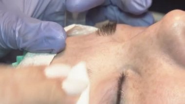 Kaş güzellik salonunda, üstat kaşlarla ilgilenir. Kadın kaşlarının tasarımı ve boyaması ve kaplaması. Renk eşleşmesi. Kozmetik bir araçla düzeltme.