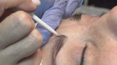 Kaş güzellik salonunda, üstat kaşlarla ilgilenir. Kadın kaşlarının tasarımı ve boyaması ve kaplaması. Renk eşleşmesi. Kozmetik bir araçla düzeltme.