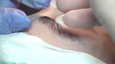 Kaş güzellik salonunda, üstat kaşlarla ilgilenir. Kadın kaşlarının tasarımı ve boyaması ve kaplaması. Renk eşleşmesi. Kozmetik bir araçla düzeltme.