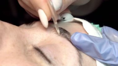 Kaş güzellik salonunda, üstat kaşlarla ilgilenir. Kadın kaşlarının tasarımı ve boyaması ve kaplaması. Renk eşleşmesi. Kozmetik bir araçla düzeltme.