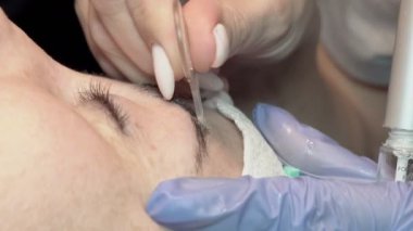 Kaş güzellik salonunda, üstat kaşlarla ilgilenir. Kadın kaşlarının tasarımı ve boyaması ve kaplaması. Renk eşleşmesi. Kozmetik bir araçla düzeltme.