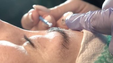 Kaş güzellik salonunda, üstat kaşlarla ilgilenir. Kadın kaşlarının tasarımı ve boyaması ve kaplaması. Renk eşleşmesi. Kozmetik bir araçla düzeltme.