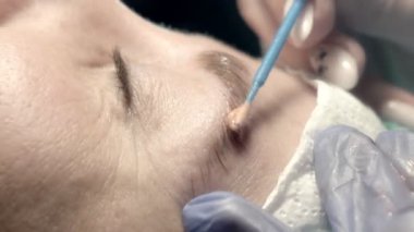 Kaş güzellik salonunda, üstat kaşlarla ilgilenir. Kadın kaşlarının tasarımı ve boyaması ve kaplaması. Renk eşleşmesi. Kozmetik bir araçla düzeltme.