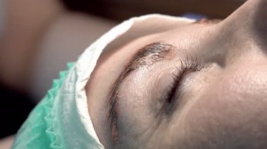 Kaş güzellik salonunda, üstat kaşlarla ilgilenir. Kadın kaşlarının tasarımı ve boyaması ve kaplaması. Renk eşleşmesi. Kozmetik bir araçla düzeltme.