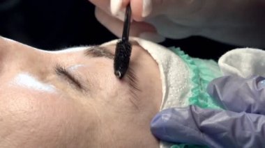 Kaş güzellik salonunda, üstat kaşlarla ilgilenir. Kadın kaşlarının tasarımı ve boyaması ve kaplaması. Renk eşleşmesi. Kozmetik bir araçla düzeltme.