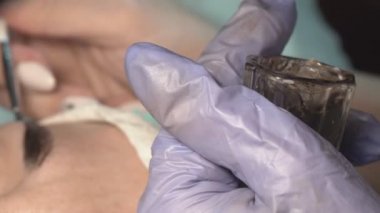 Kaş güzellik salonunda, üstat kaşlarla ilgilenir. Kadın kaşlarının tasarımı ve boyaması ve kaplaması. Renk eşleşmesi. Kozmetik bir araçla düzeltme.