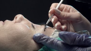 Kaş güzellik salonunda, üstat kaşlarla ilgilenir. Kadın kaşlarının tasarımı ve boyaması ve kaplaması. Renk eşleşmesi. Kozmetik bir araçla düzeltme.