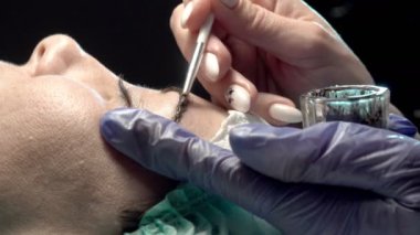 Kaş güzellik salonunda, üstat kaşlarla ilgilenir. Kadın kaşlarının tasarımı ve boyaması ve kaplaması. Renk eşleşmesi. Kozmetik bir araçla düzeltme.