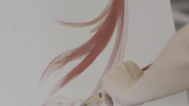 Ressam eli resim yapıyor. Bir sanat stüdyosunun tuvalinde fırçayla fırçalanmış bir kadın elinin yakın çekimi.