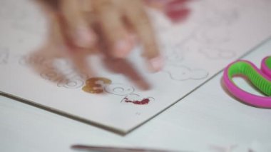 Parlak pudrayla çocuk resimleri yapar. Çocuk kağıt çizimlerini parlak tozla boyuyor, yapıştırıcıya dayanarak küçük parıltıları ovuyor. Çocukların yaratıcılığını geliştirir.