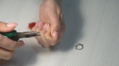 Kadın ellerle mücevher yapıyor. Evde el işi. Bir kadın kendi elleriyle kadınlar için ipliklerden mücevher yapar..