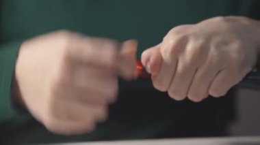 Kadın ellerle mücevher yapıyor. Evde el işi. Bir kadın kendi elleriyle kadınlar için ipliklerden mücevher yapar..