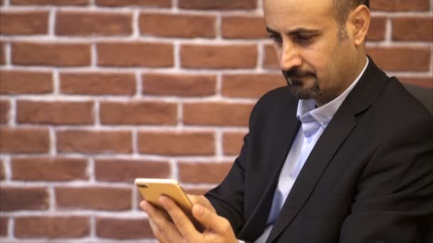 Hombre de negocios usando el teléfono inteligente - Fondo de pared de ladrillo — Vídeos de Stock