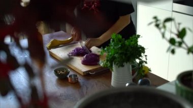 Kadın mutfakta ahşap bir masa üzerinde taze kırmızı lahana doğrama