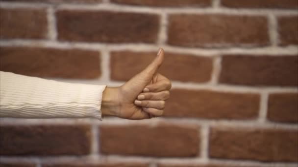 Γυναίκα χέρι thumbs up - τοίχο από τούβλα παρασκήνιο — Αρχείο Βίντεο